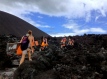 a group of white people carrying orange bags are climbing a volcano in Nicaragua